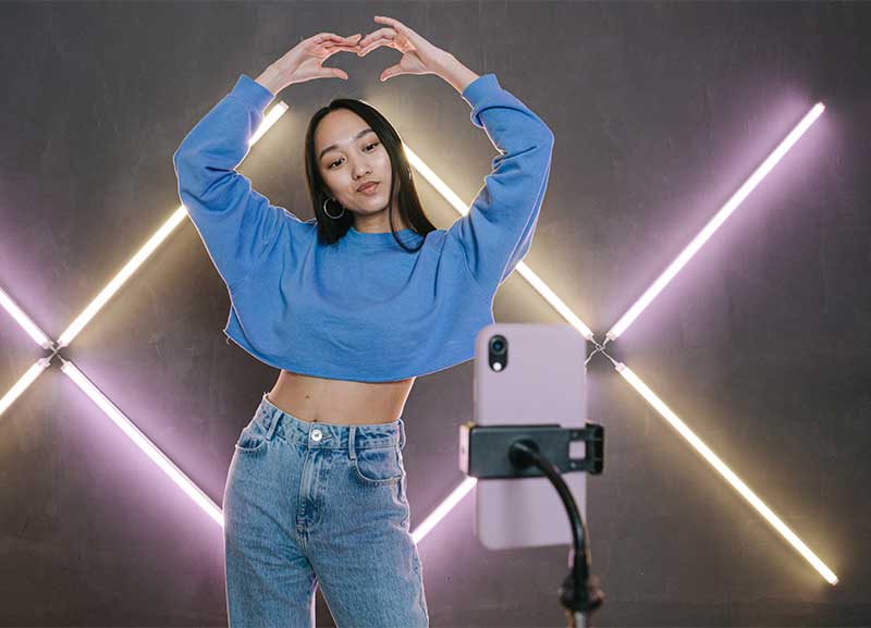 Girl standing in front of a phone screen in a dance pose, recording a TikTok dance.