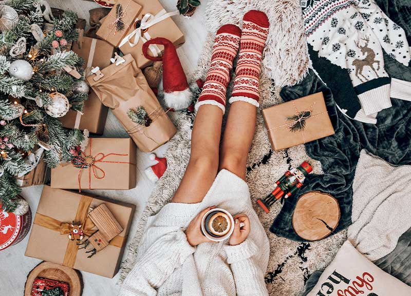 Women's legs in fuzzy socks surrounded by holiday decor